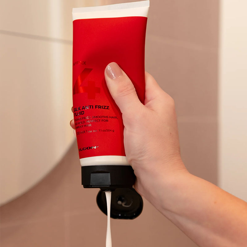 Tubo bianco con sleeve rossa con scritte nere e tappo flip top nero che viene premuto da una mano.