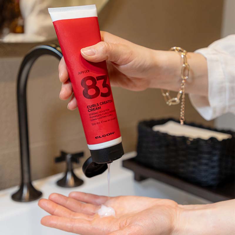 Tubo bianco con sleeve rossa con scritte nere e tappo flip top nero che viene erogato sul palmo di una mano.